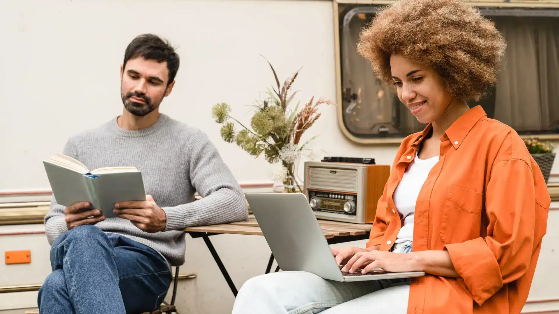 man and woman sat by motorhome with a laptop