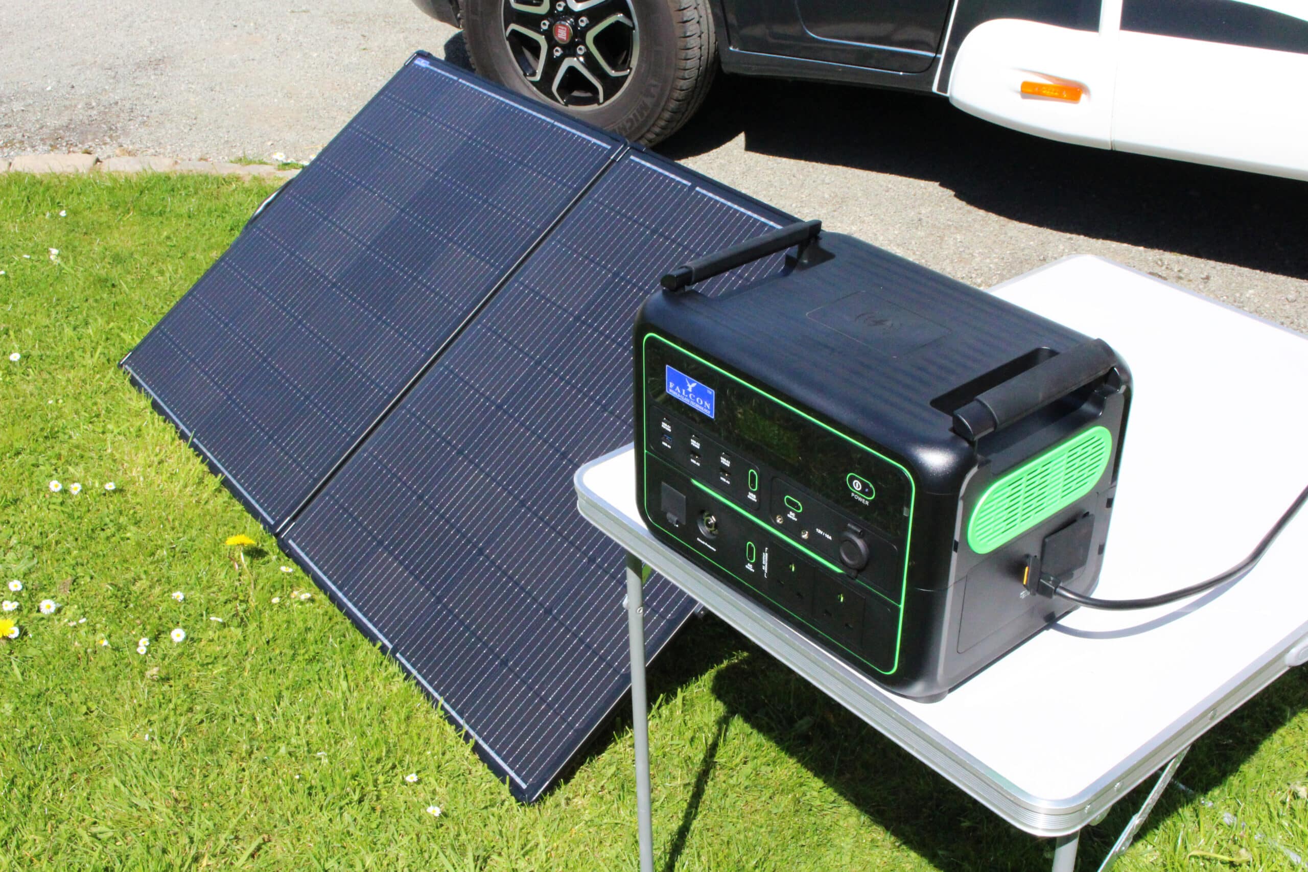 Falcon 270W folding solar panel set up beside the Falcon 1200W Portable Power Station on grass.